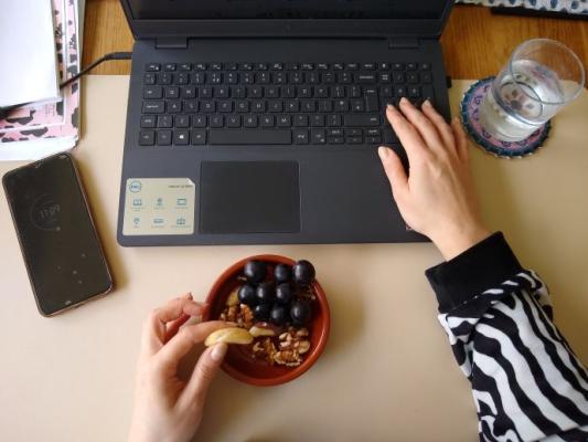 a woman's hands while at the laptop eating healthy snacks