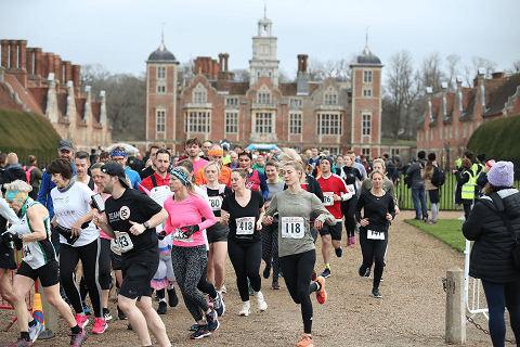 People running in numbered bibs in front of Blickling Hall