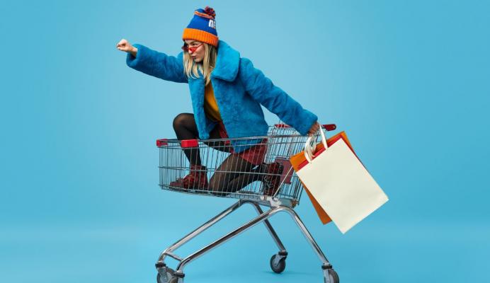 Colourfully dressed girl sat in the shopping cart in a power pose