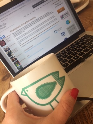 Claire's hand and mug with laptop inthe background