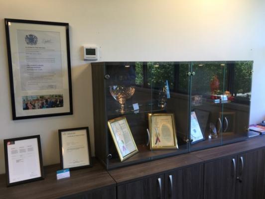 Queens Award Certificate on a wall next to trophy cabinet. Image courtesy of Global Inkjet Systems