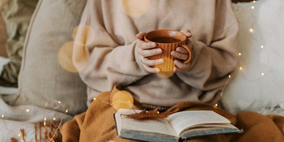 A photo of a person in a jumper holding a cup of hot drink