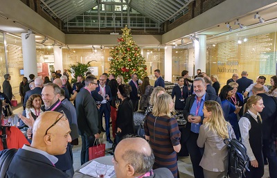 Photo of event attendees in a room with christmas tree behind them