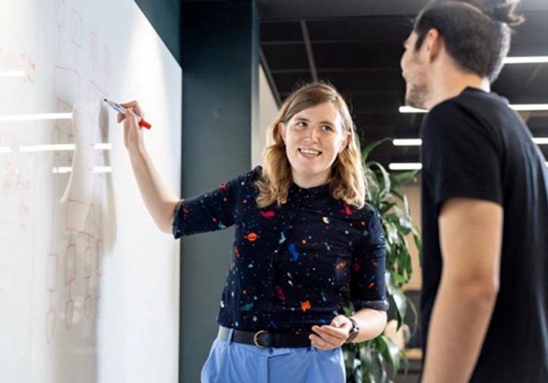 Female smiling while writing on a whiteboard