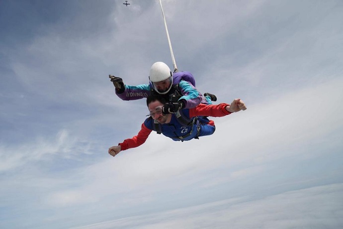 A person skydiving with an instructor on his back