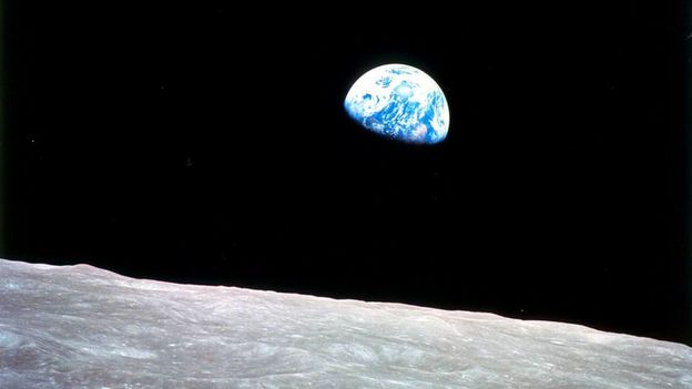 The earth rising beyond the moon in space