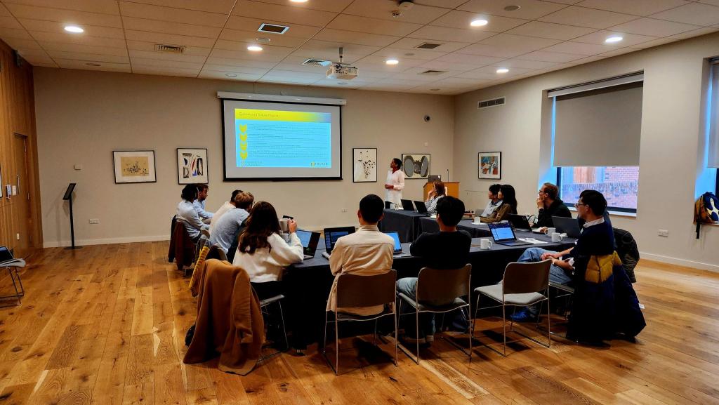 A group of people seated around a table watching a presentation