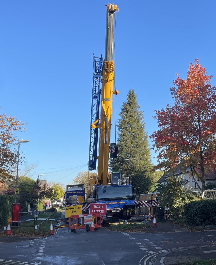 Large crane prepares to lift modular home into position