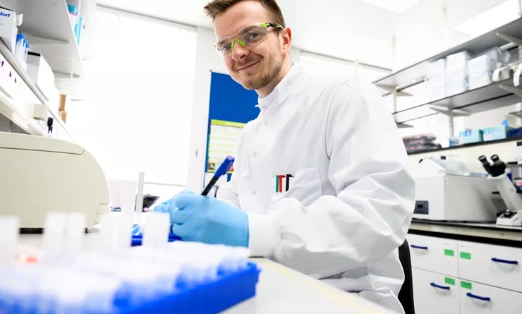 Lab technician looking at the camera, smiling whilst carrying out work