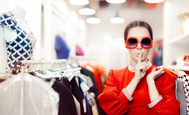 Woman in clothing store saying 'shush' and putting a finger to her lips