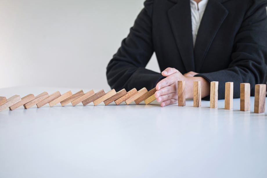 Person stopping a line of blocks from continuing to fall over