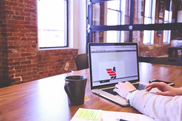 Girl sitting at a laptop with coffee next to her