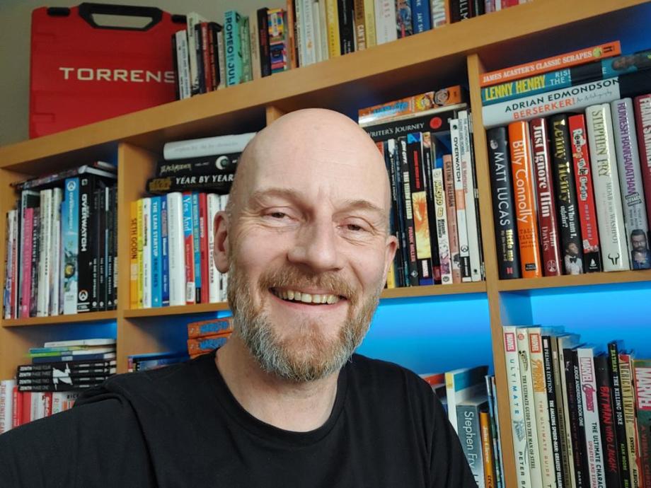 A smiling man in front of a bookcase