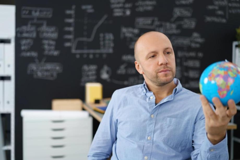 Pensive businessman contemplating global markets holding a small globe