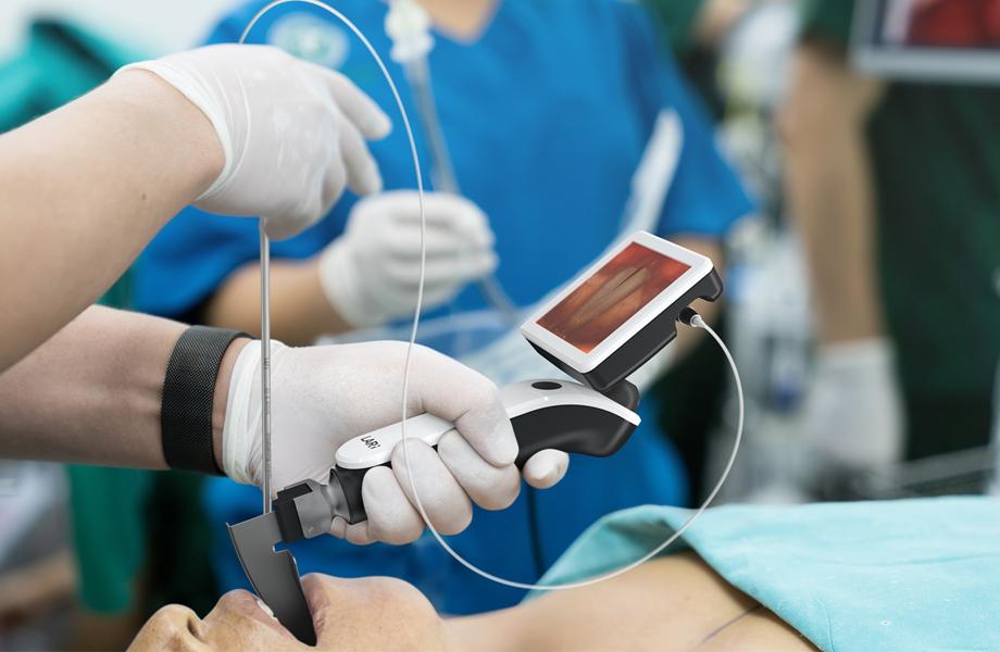 Anaesthetist using video-enabled stylet with display attached to laryngoscope to intubate patient for surgery