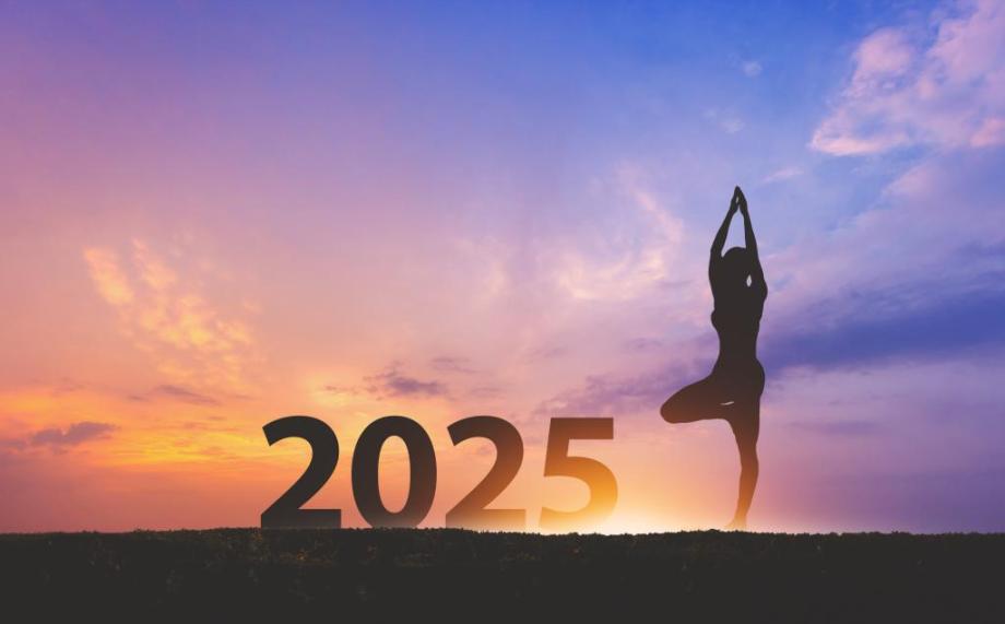 Sunrise and purple sky behind large 2025 numbers and a silhouette of a yoga pose