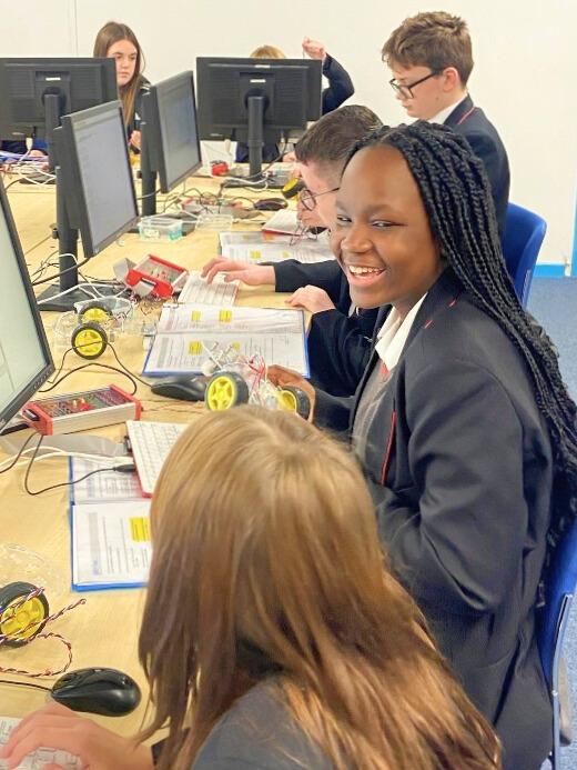 A girl smiles at her friend while around her children programme motorised buggies at the Centre for Computing History