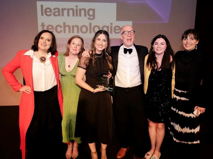 Simon on stage receiving an award, surrounded by team members