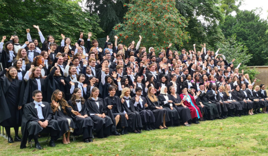 Group of postgraduates in College with hands in the air