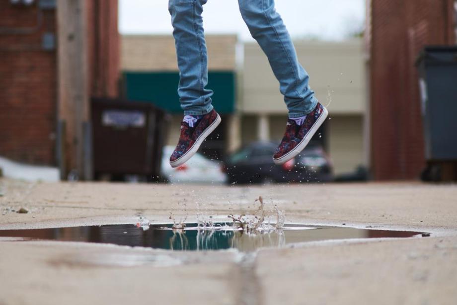 A pair of feet jumping from a puddle.