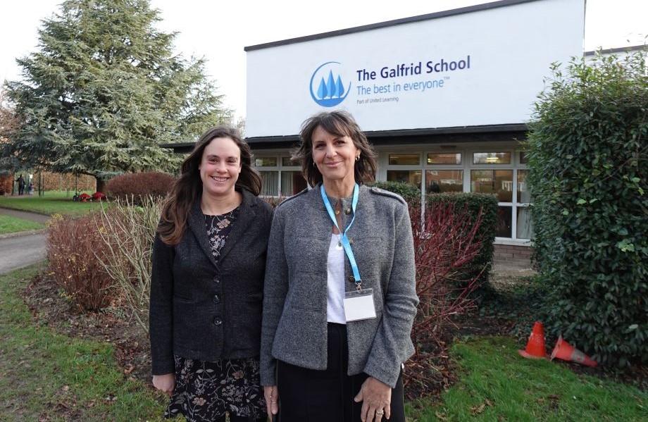 Two women standing in front of Galfrid school sign smiling