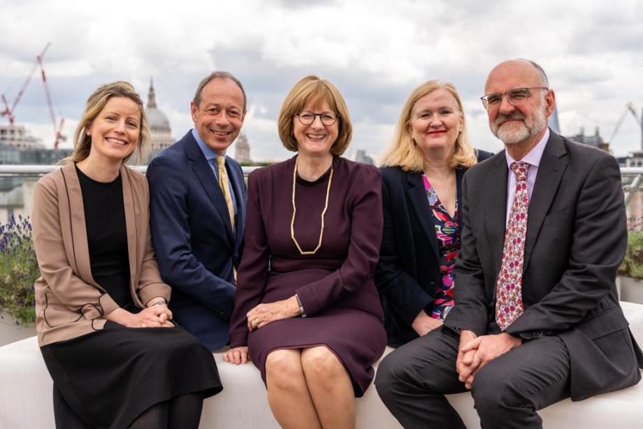 Five lawyers sit side-by-side and smile at the camera.