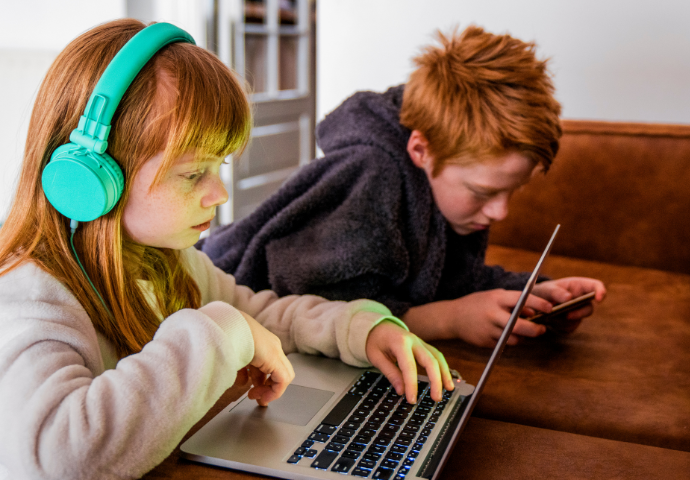 2 children using a laptop and a mobile 