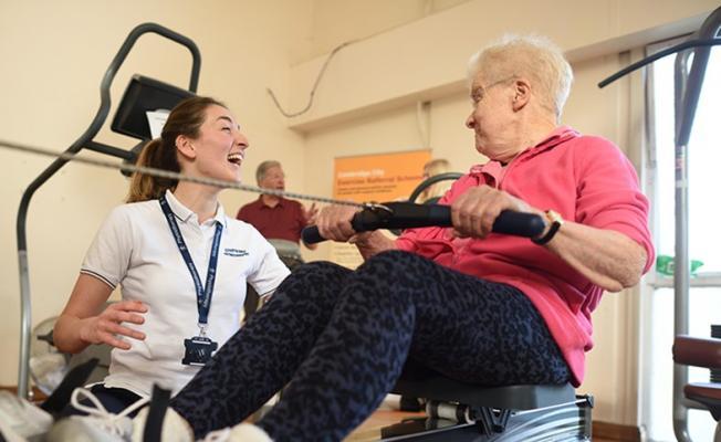 older woman on rowing machine with younger trainer