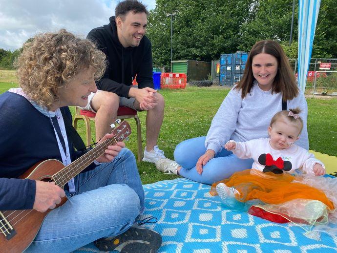 lady playing a guitar to child and parents  