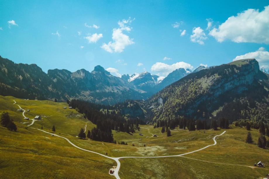 Pathways along grass hillsides with mountains in the distance