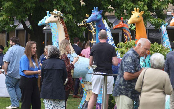 people standing next to Break's giraffe