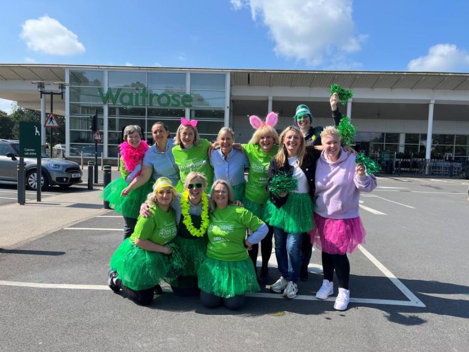 A group of females dressed in green outside a supermarket