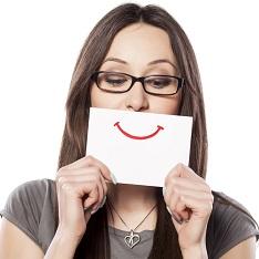 woman holds paper smile over her mouth