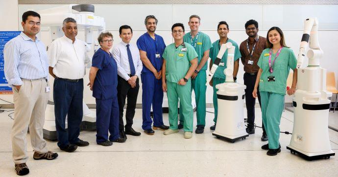 group of medical staff standing next to a surgical robot 