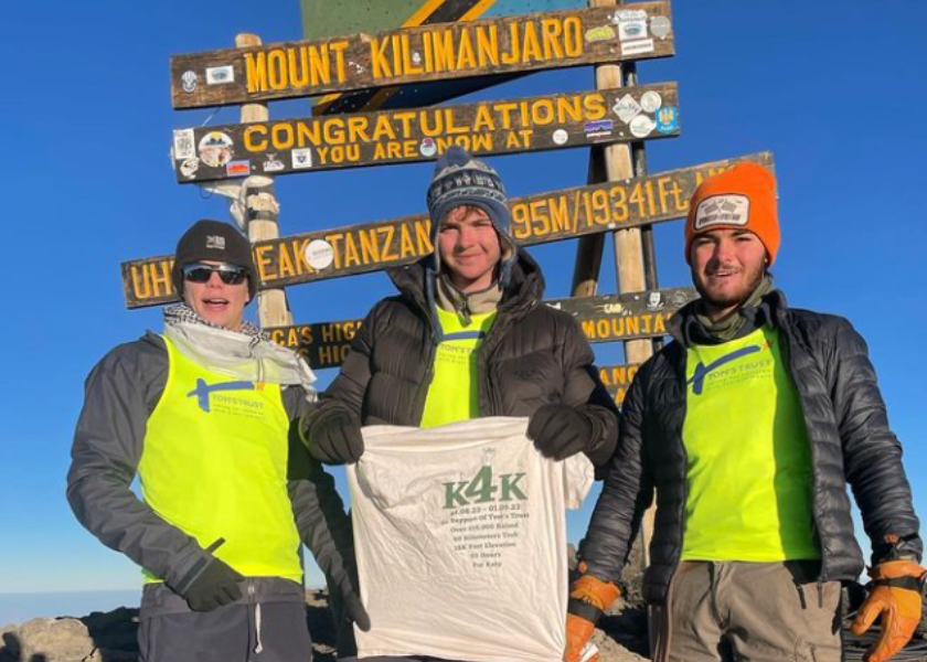 the 3 climbers at the top of the summit, wearing Tom's Trust t-shirts