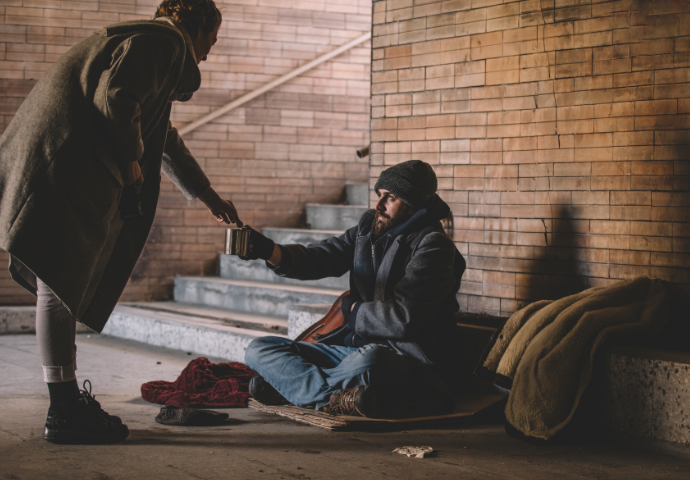 woman giving homeless man money 