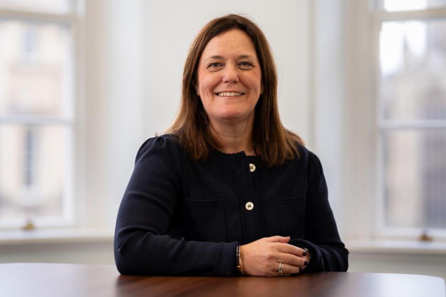 Photograph of Stone King's new CEO, Vicky Brackett, smiling. She is sat down at a table with her hands clasped on the table in front of her.