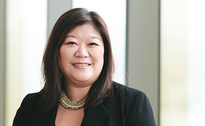 Lady with brown hair in a black suit jacket smiling at the camera