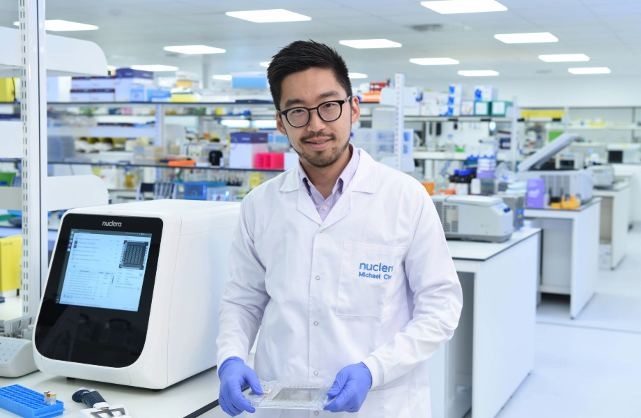 Dr Michael Chen standing with eProtein Discovery holding smart cartridge in the lab