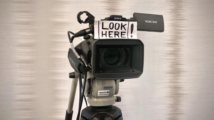 camera on tripod with sign that says' Look here'