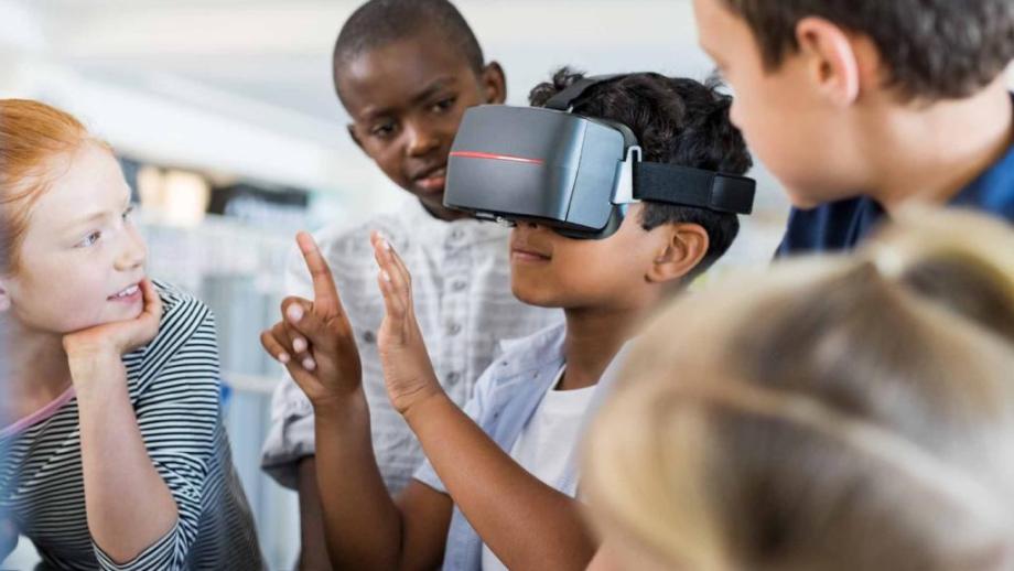 A child holds their hands up with a VR headset on their head