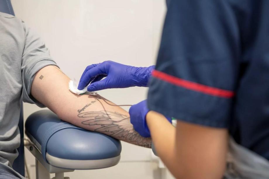 Photo of patient's arm providing a blood sample, with nurse's hand carrying out the procedure