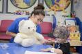 Paediatric day unit healthcare play specialist Gaby Catrisano showing two-year-old Jaymen Woolston Snowy the bear. Snowy is fitted with a Hickman line, which is used for the administration of chemotherapy or other medications, as well as for the withdrawal of blood for analysis.
